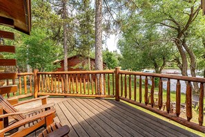 Eine Holzterrasse mit Geländer, umgeben von Bäumen und mit Blick auf ein Gewässer.