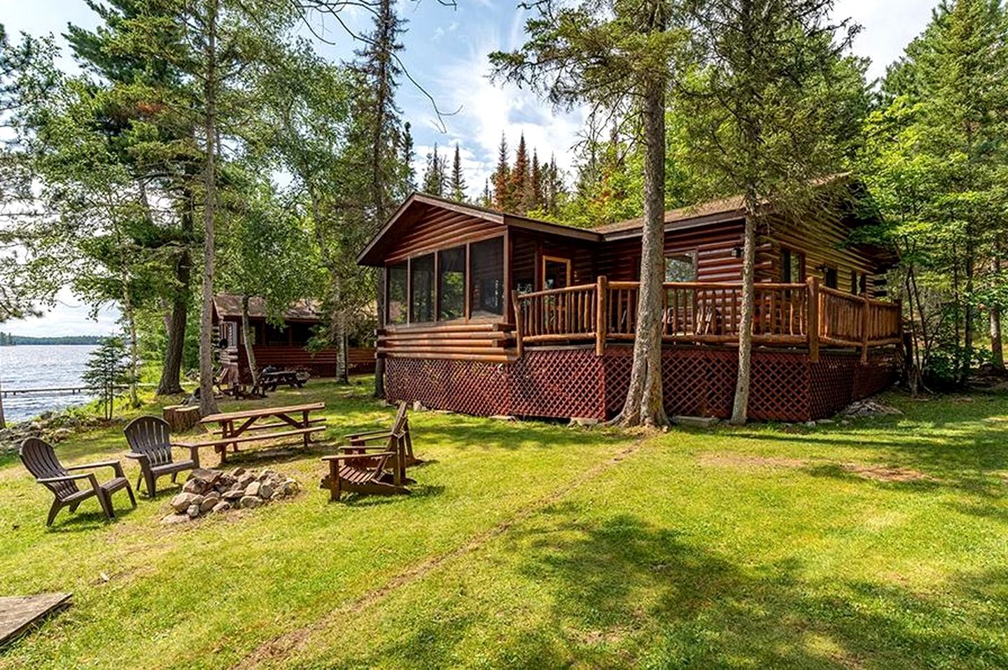 Eine Holzhütte mit Terrasse, umgeben von Bäumen und einem See.