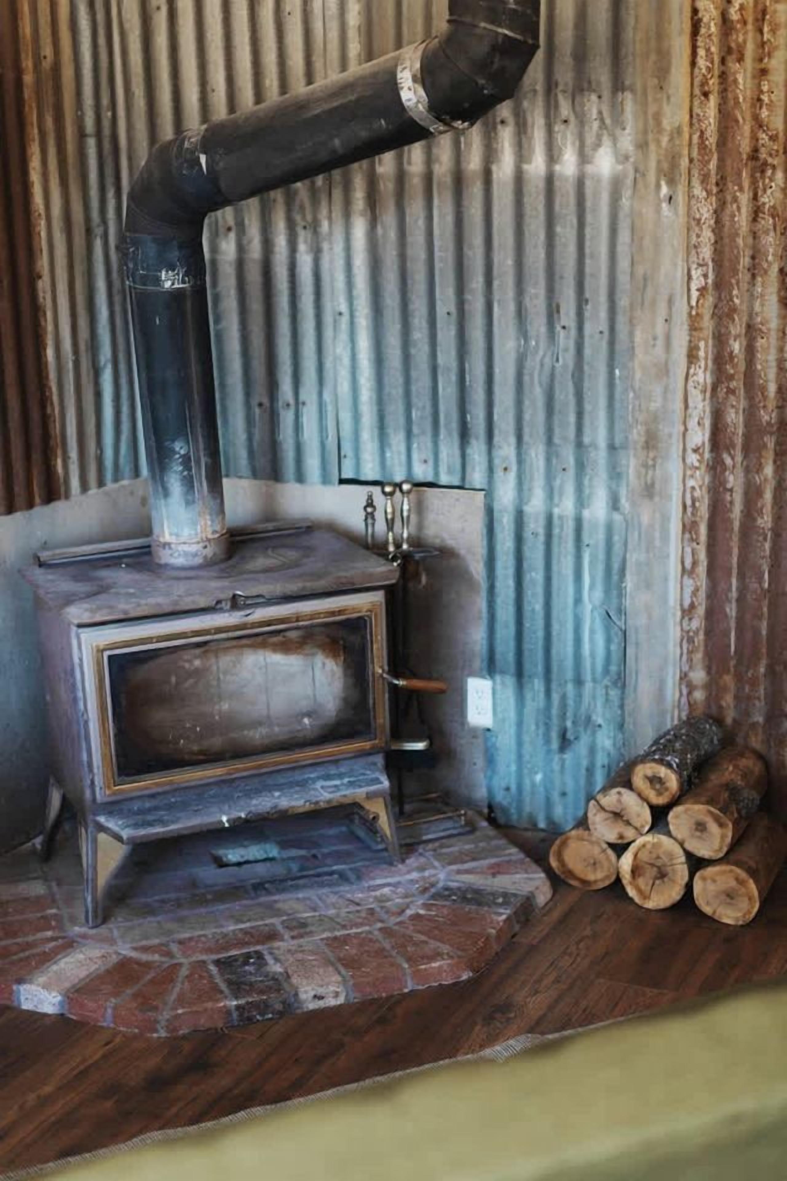 A wood-burning stove with a chimney, a metal door, and a stone base.