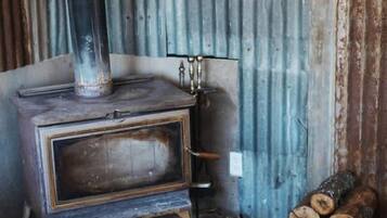 A wood-burning stove with a chimney, a metal door, and a stone base.