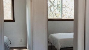 Una habitación con cama, una silla y ventana con vista a árboles.