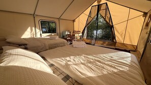 Eine Zeltdominierung mit zwei Betten, einem Tisch, Stühlen und einem Fenster.