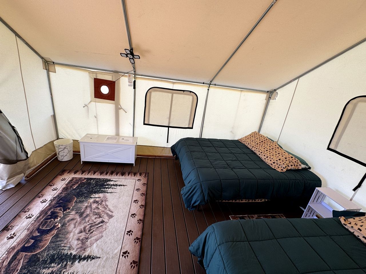 A tent with two beds, a small table, and a window.