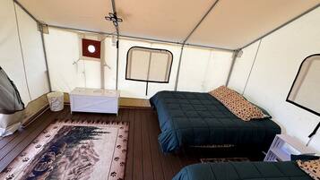 A tent with two beds, a small table, and a window.