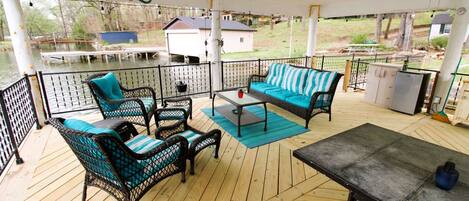 A covered outdoor deck with wicker furniture, a table, and a refrigerator.