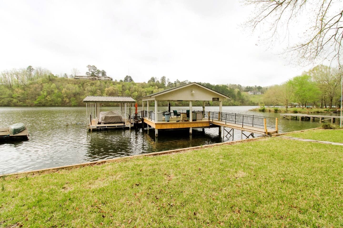 A lakeside dock with a covered seating area and a small boat.