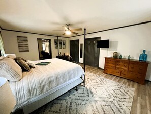 Ein Schlafzimmer mit Bett, Kommode, Deckenventilator und Fernseher.
