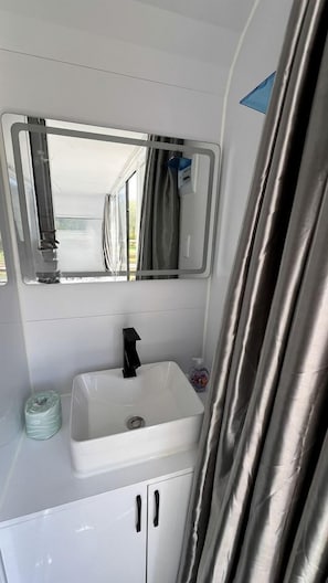 A bathroom with a white sink, a mirror, and a shower curtain.