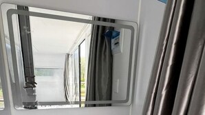 A bathroom with a white sink, a mirror, and a shower curtain. - Sleek and Modern Glamping Pod in Klamath, Perfect for a Getaway near the Pacific Ocean (Klamath)
