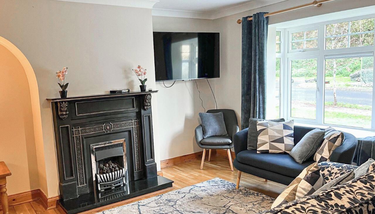 A modern living room with a fireplace, a sofa, a TV, and a window with curtains.