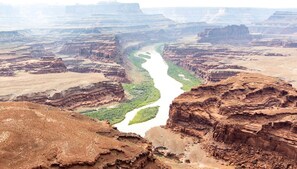 Paisaje de cañón con río, acantilados y vegetación escasa.