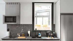 A modern kitchen with a built-in microwave, a window with a view of the outdoors, and a stainless steel refrigerator. - Limehome Madrid Calle de Bolivia (Madrid)