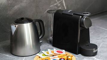 Una encimera de cocina con una cafetera, un hervidor y un soporte para cápsulas de café.