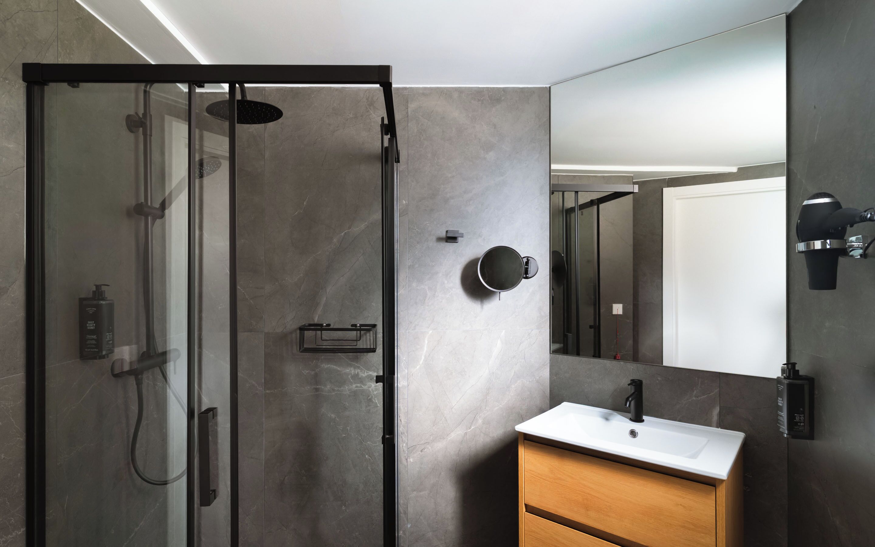 A modern bathroom with a glass-enclosed shower, a white sink, and a wooden cabinet.