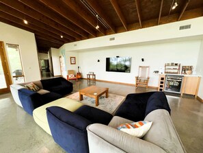 A spacious living room with a high ceiling, a kitchen area, and a dining table. - Gorgeous and Secluded Cabin with Lakefront Views and a Rooftop Terrace, Perfect for a Peaceful Weekend Away (Edgemont)