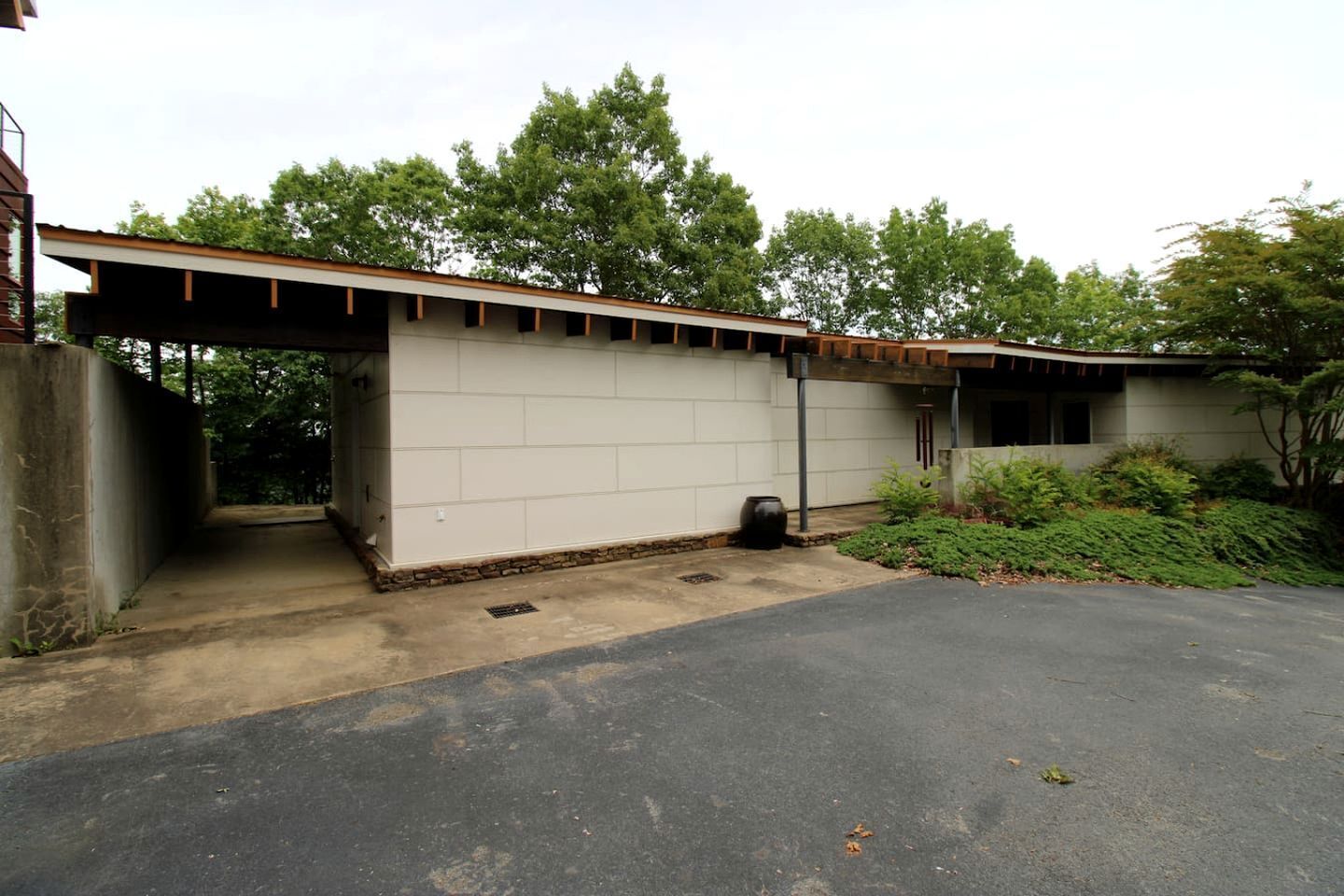 A building with a garage, a covered outdoor area, and a paved driveway.