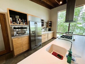 A modern kitchen with built-in appliances, a large window, and a view of the outdoors. - Gorgeous and Secluded Cabin with Lakefront Views and a Rooftop Terrace, Perfect for a Peaceful Weekend Away (Edgemont)