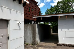A garage entrance with a concrete wall, a metal door, and a brown building with windows. - Gorgeous and Secluded Cabin with Lakefront Views and a Rooftop Terrace, Perfect for a Peaceful Weekend Away (Edgemont)