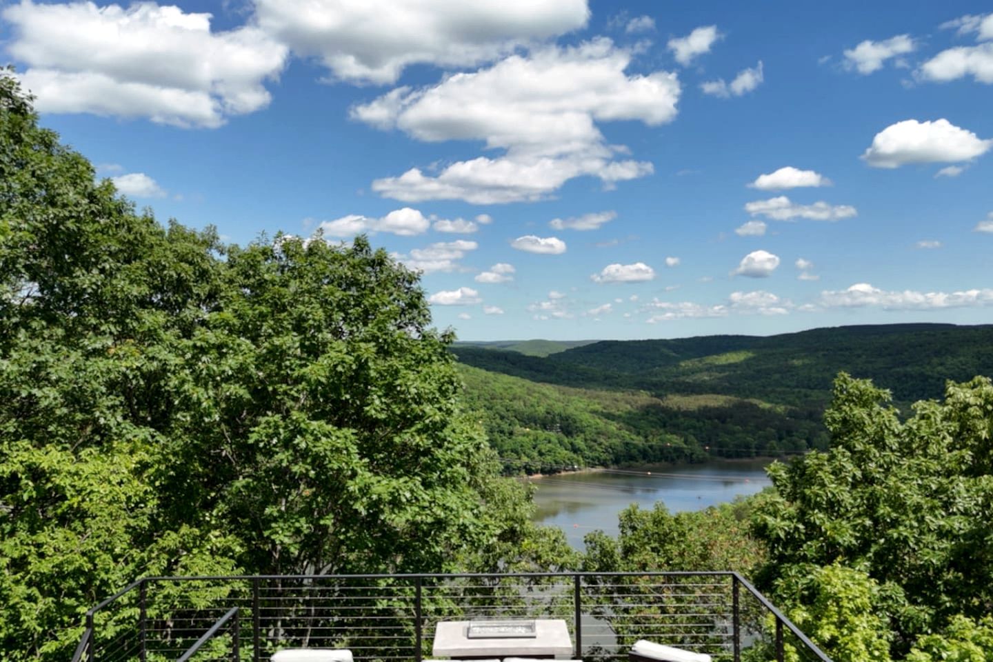 Un mirador con un lago, colinas boscosas y un cielo despejado.