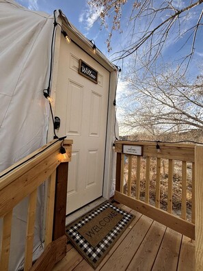 A wooden deck with a welcome mat, a door labeled 'Willow,' and a sign that reads 'Welcome.'