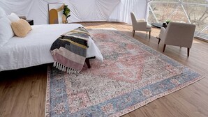 A spacious tented room with a bed, a patterned rug, and a view of the landscape. - Amazing Dome with Stunning Sights in Wayne County, Utah (Torrey)