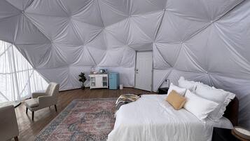 A spacious room with a large bed, a small desk, and a chair.