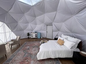 A spacious room with a large bed, a small desk, and a chair.
