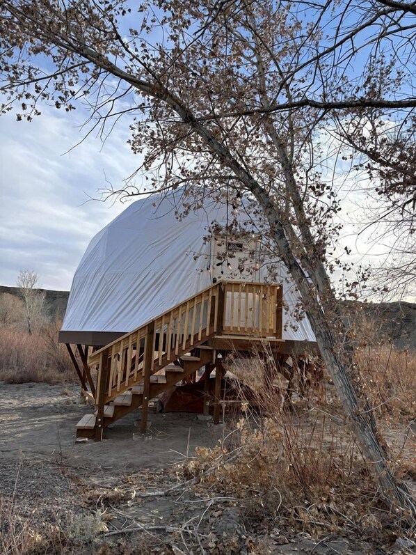 A dome-shaped structure with a wooden staircase leading up to a deck.