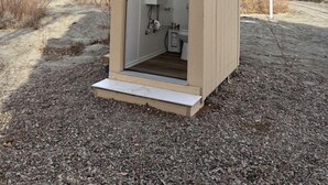 A small, single-room structure with a door, a window, and a built-in sink. - Amazing Dome with Stunning Sights in Wayne County, Utah (Torrey)