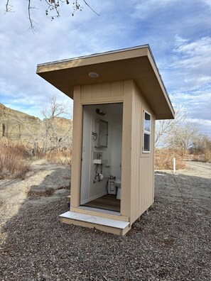 A small, single-room structure with a door, a window, and a built-in sink.