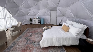 A spacious room with a large bed, a small desk, and a chair.