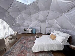 A spacious room with a large bed, a small desk, and a chair.