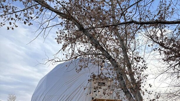 A dome-shaped structure with a wooden staircase leading up to a deck. - Amazing Dome with Stunning Sights in Wayne County, Utah (Torrey)