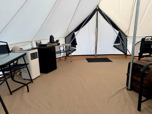 L'intérieur d'une tente, avec une table, un chauffage et un espace pour dormir.