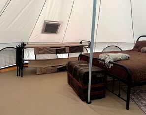Une tente équipée d’un lit, d’un coffre de rangement et d’une fenêtre.