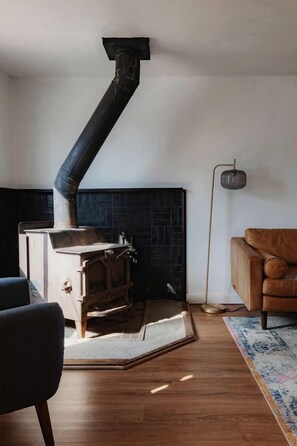 A room with a wood-burning stove, a leather sofa, and a patterned rug. - Spacious Four Bedroom Cabin on Private Land in Sierra National Forest, Perfect for a Tranquil Weekend in Nature with Family (Dunlap)