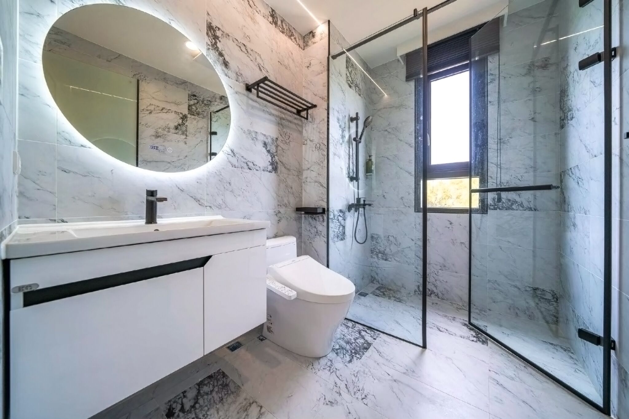 A modern bathroom with a marble floor, a white sink, and a glass-enclosed shower area.