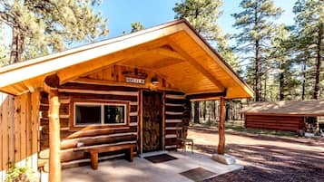 A log cabin with a porch, a window, and a door.