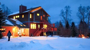 Una casa de madera de varios pisos con un balcón, rodeada de nieve.