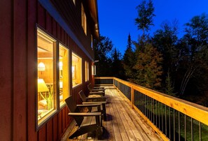 En træterrasse med udendørs møbler, gelænder og en bygning med vinduer.