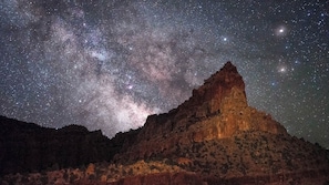 A starry night sky over a mountain with a prominent peak.
