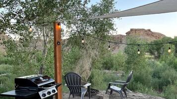 An outdoor patio with a grill, chairs, and a table.
