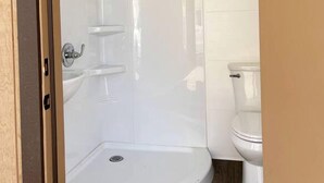 Et badeværelse med brusebad, toilet og vask.