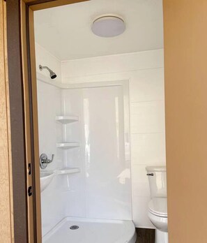 Een badkamer met een douche, toilet en wastafel.