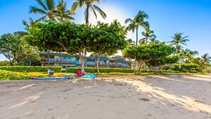 Een strandhotel met een zwembad, palmbomen en een heldere lucht.
