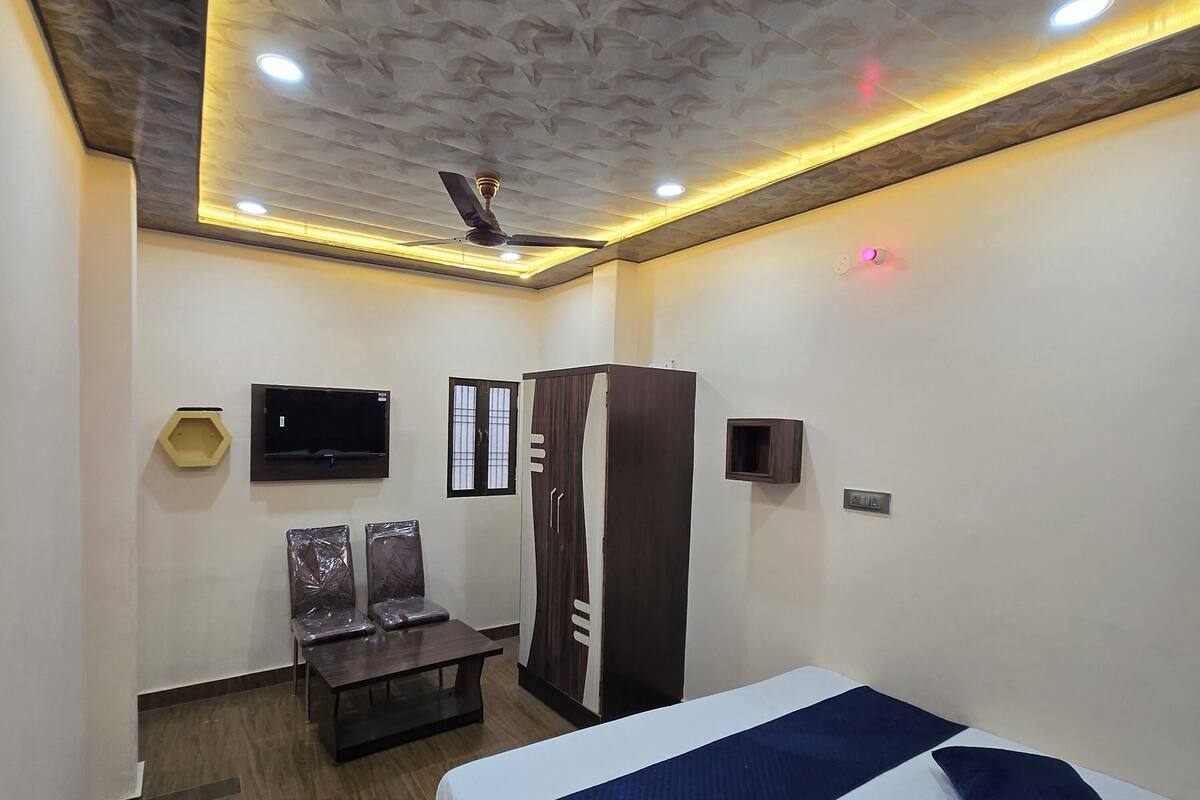 A hotel room with a bed, a desk, a wardrobe, a TV, and a ceiling fan.