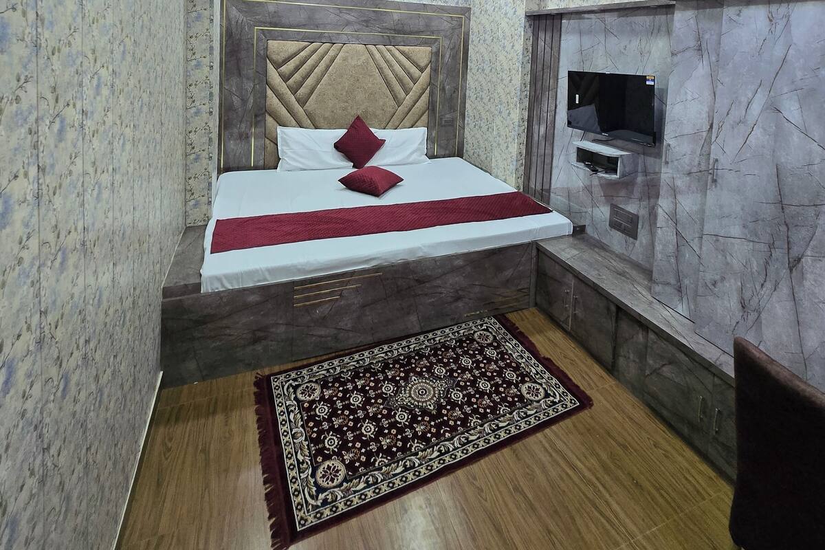 A bedroom with a bed, a TV, and a ceiling fan.