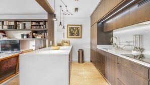 Eine moderne Küche mit Holzschränken, einer weißen Arbeitsplatte und Pendelleuchten.