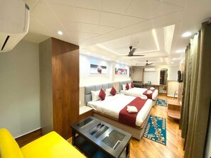 A hotel room with two beds, a small table, a chair, a mirror, and a ceiling fan. - Shree Shanteshwar Mahadev Inn (Varanasi)
