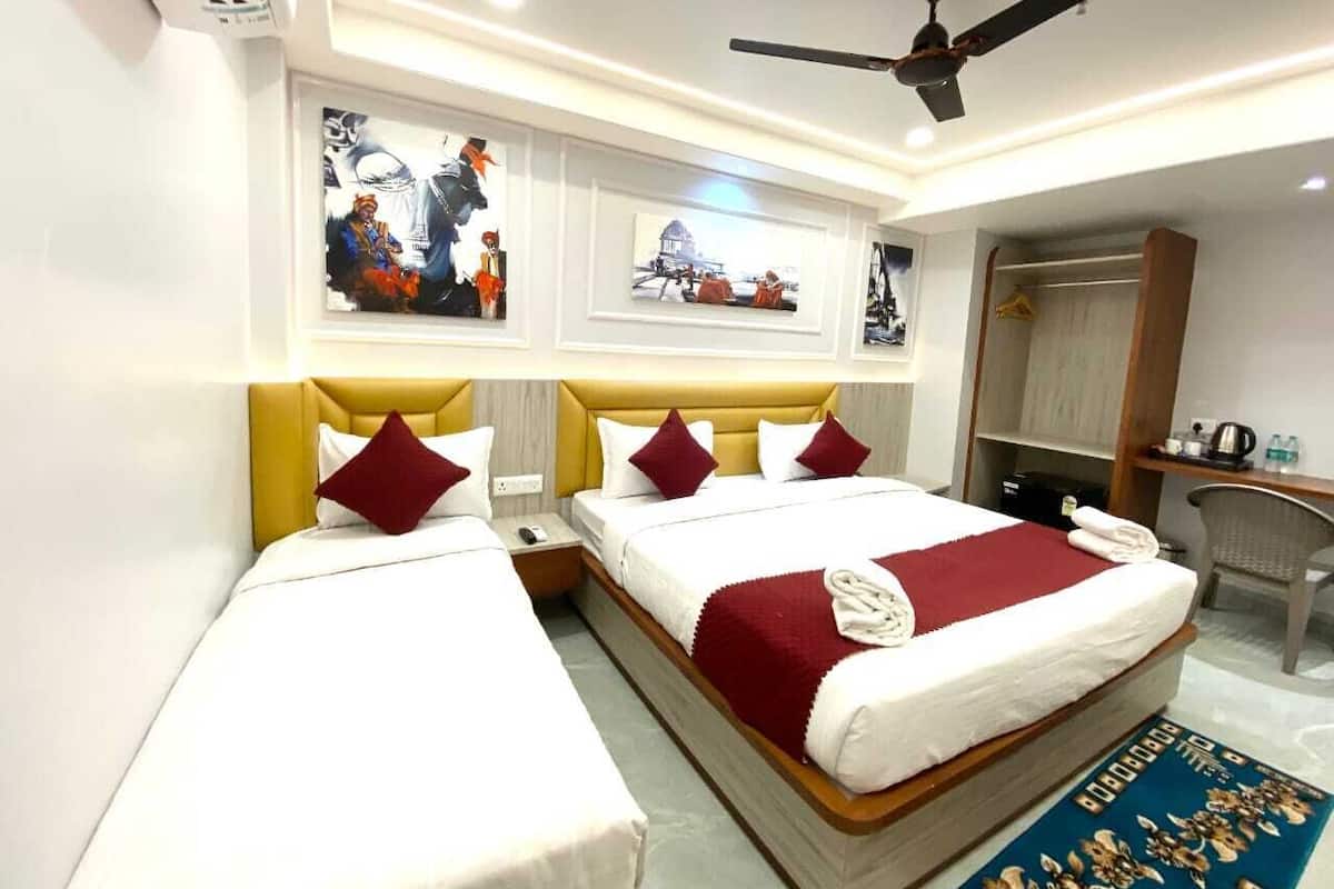 A hotel room with two beds, a ceiling fan, a desk, and a chair.